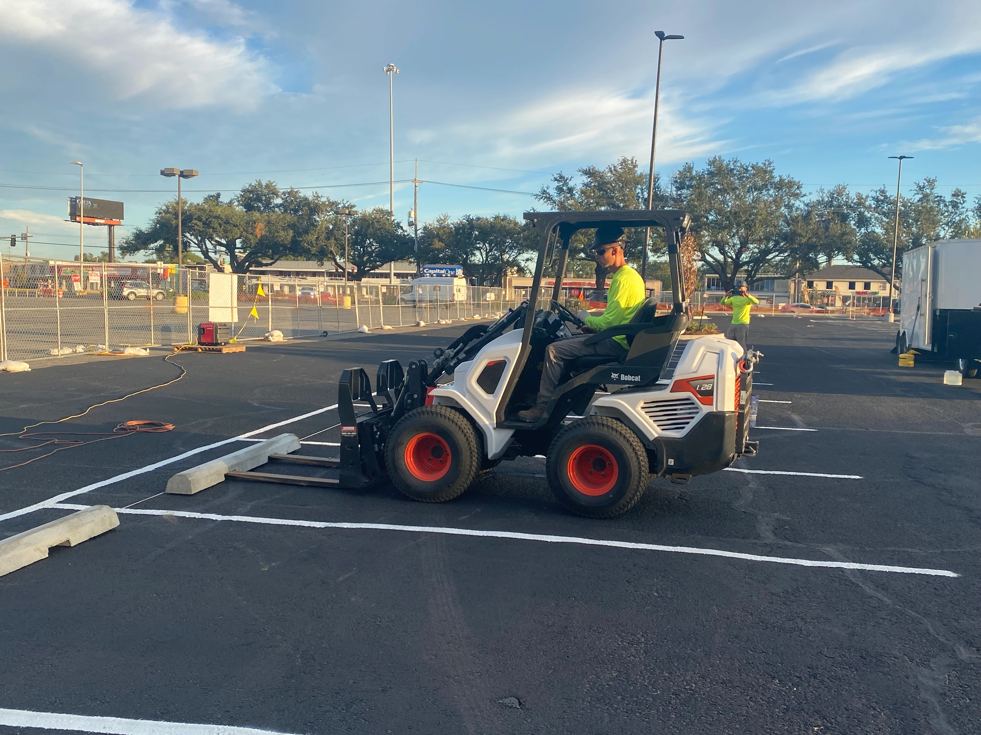 Wheel stop installation New Orleans — Bobcat placing concrete wheel stops in parking lot